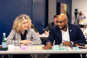 Two people sitting at a table, talking and smiling at the Junction.